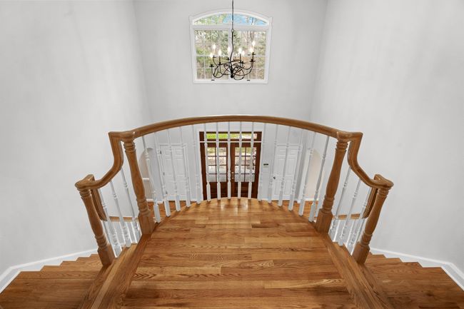 A stunning view from the second-floor landing showcases the elegant double staircase, chandelier, and stately front entryway. | Image 33