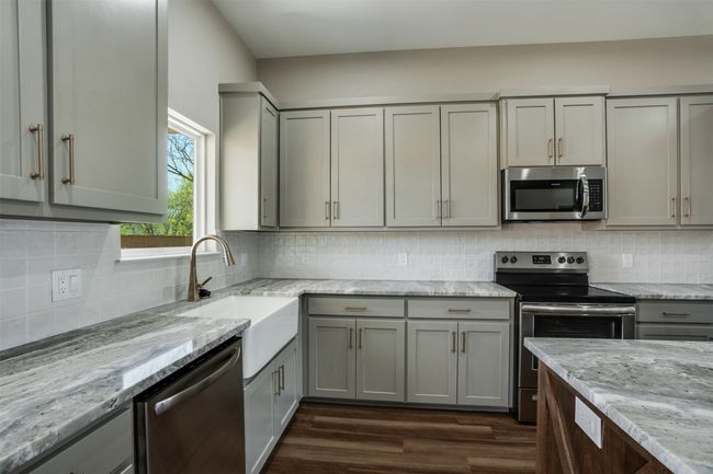 Kitchen featuring stainless steel appliances, gray cabinetry, a sink, and tasteful backsplash | Image 9