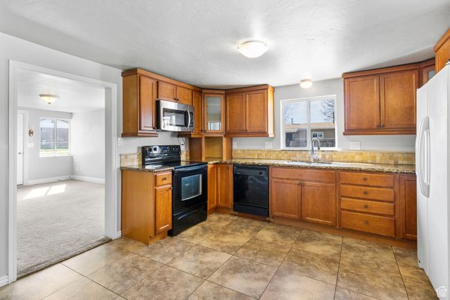 Kitchen featuring a sink, brown cabinetry, black appliances, and a healthy amount of sunlight | Image 26