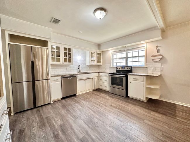 Kitchen featuring stainless steel appliances, crown molding, backsplash, open shelves, and wood finished floors | Image 11