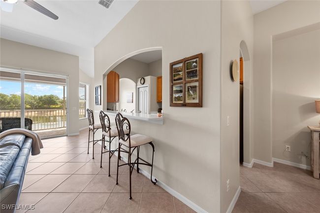 Kitchen featuring visible vents, light tile patterned floors, a kitchen bar, brown cabinetry, and ceiling fan | Image 14