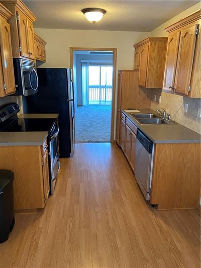 Kitchen featuring sink, dishwasher, range, light hardwood / wood-style floors, and decorative backsplash | Image 2