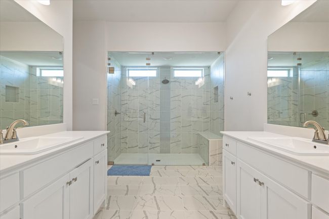 Bathroom featuring healthy amount of natural light, a stall shower, marble look tile flooring, and two vanities | Image 22