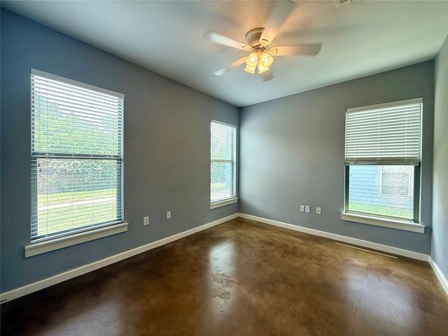 Spare room with finished concrete floors, baseboards, and a ceiling fan | Image 12