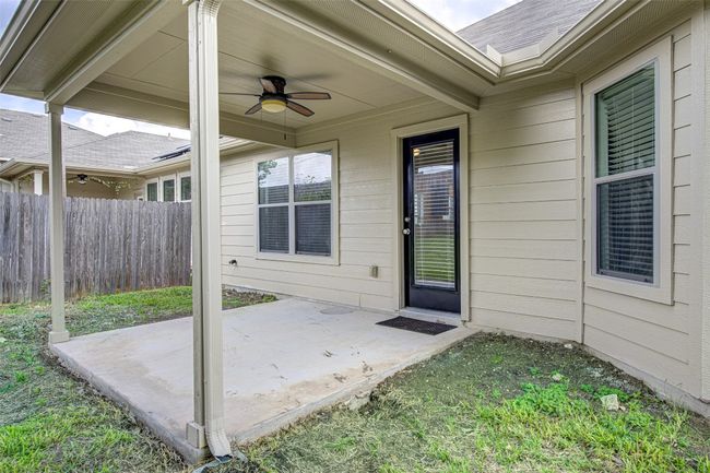 Entrance to property featuring a patio, ceiling fan, and roof with shingles | Image 30