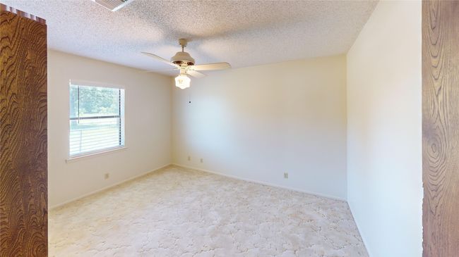 Empty room with light carpet, a ceiling fan, a textured ceiling, and baseboards | Image 13