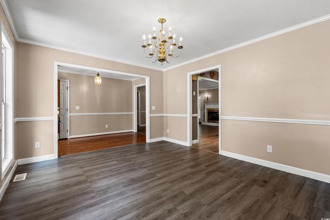 Spare room featuring a chandelier, dark wood finished floors, crown molding, and a fireplace | Image 31