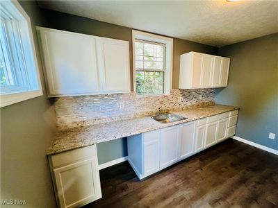 Remodeled kitchen with new counters and stainless sink, white cabinetry and vinyl plank flooring. | Image 2