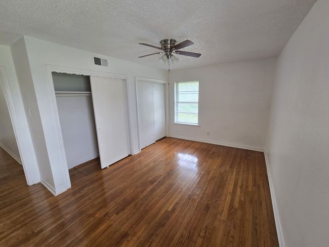 Unfurnished bedroom featuring dark wood-type flooring, multiple closets, a textured ceiling, and ceiling fan | Image 8