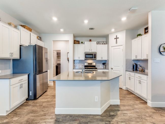 Kitchen featuring stainless steel appliances, decorative backsplash, light wood-type flooring, white cabinetry, and recessed lighting | Image 11