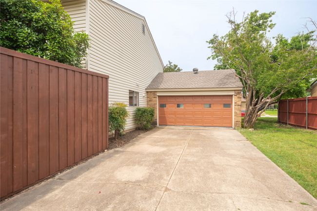 View of side of home with brick siding, concrete driveway, roof with shingles, and a garage | Image 37