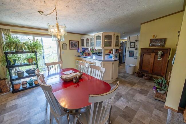 Dining area featuring crown molding, a textured ceiling, and a chandelier | Image 15