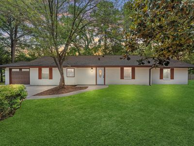 This is a single-story home featuring a brick and siding exterior, an attached garage, and a well-maintained lawn with mature trees. | Image 1