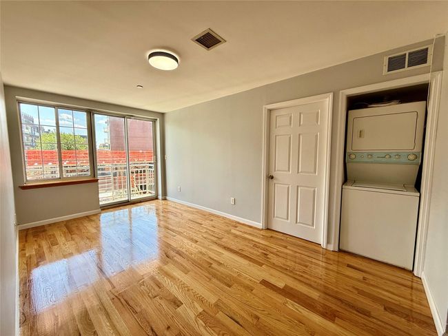 Spare room with stacked washing machine and dryer and light wood-style flooring | Image 9