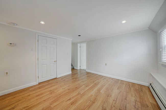 Spare room featuring lofted ceiling, a baseboard heating unit, ornamental molding, and light hardwood / wood-style flooring | Image 25