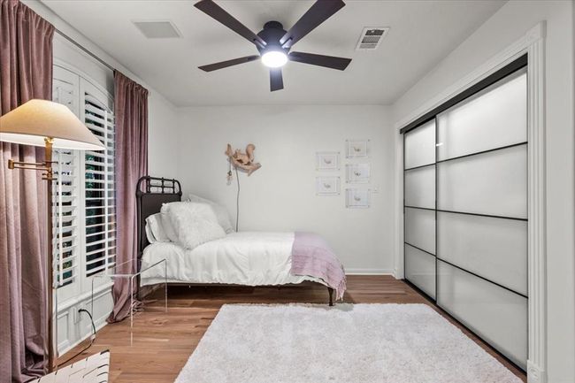This adorable bedroom is bright and fresh with modern closet doors, plantation shutters, and a soft palette perfect for all ages. | Image 28