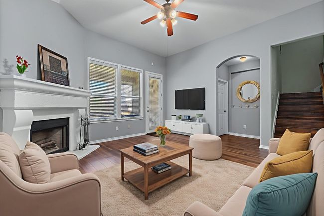 Living area featuring ceiling fan, arched walkways, stairs, and wood finished floors | Image 12