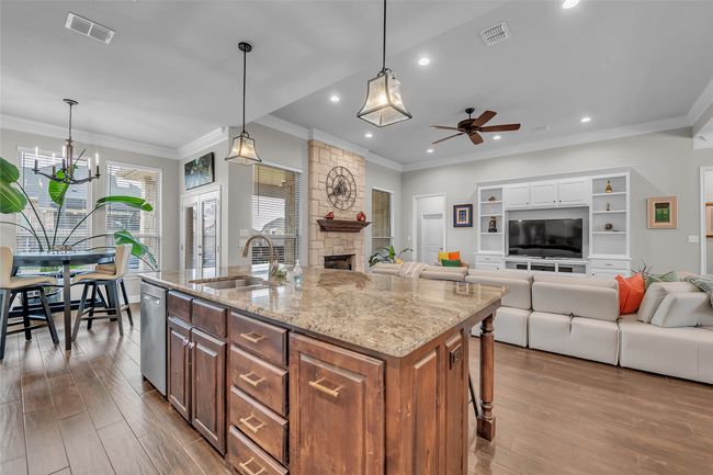 Kitchen featuring a sink, ceiling fan, recessed lighting, a stone fireplace, and open floor plan | Image 12