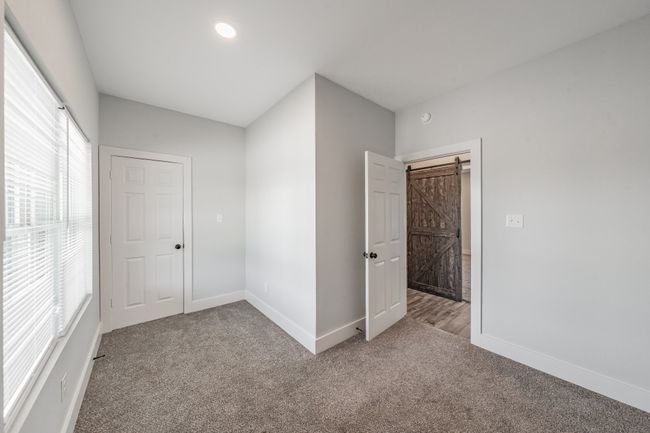 Unfurnished bedroom with carpet, baseboards, and a barn door | Image 27