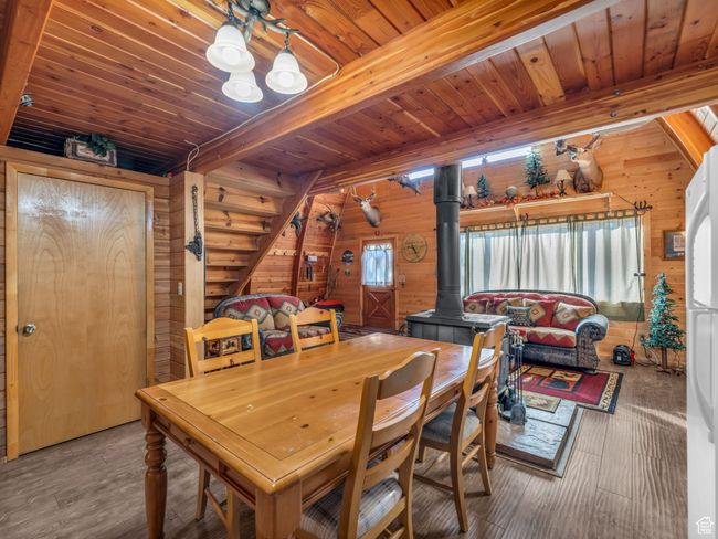 Dining space with a wood stove, a wood ceiling with exposed beams, wood walls, and wood finished floors | Image 10