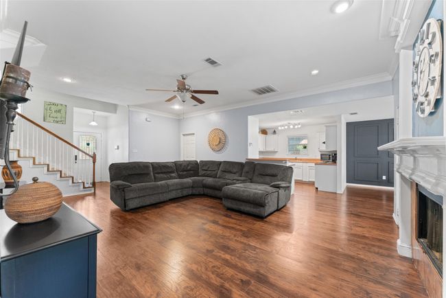 Living area featuring stairs, a ceiling fan, dark wood-style floors, a fireplace, and recessed lighting | Image 6