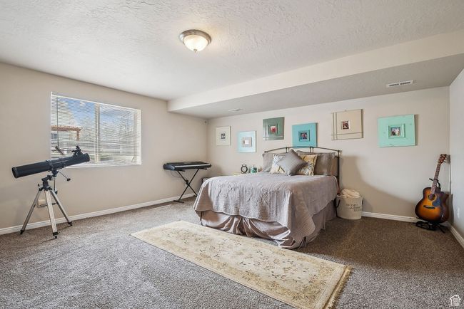 Bedroom with baseboards, visible vents, carpet, and a textured ceiling | Image 51