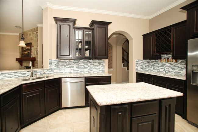 Kitchen with appliances with stainless steel finishes, a sink, tasteful backsplash, arched walkways, and crown molding | Image 9