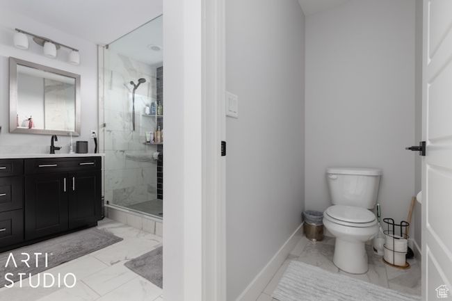 Full bath featuring a marble finish shower, marble finish floor, toilet, and vanity | Image 33