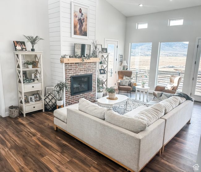 Living room featuring dark wood-style floors, a fireplace, a high ceiling, and recessed lighting | Image 5