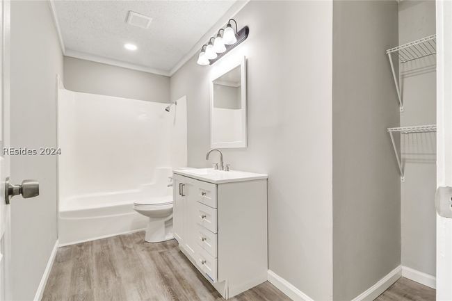 Full bathroom featuring hardwood / wood-style floors, shower / bathing tub combination, a textured ceiling, toilet, and vanity | Image 10