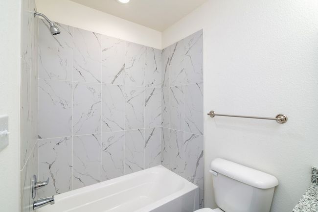 Bathroom featuring tiled shower / bath combo and toilet | Image 9