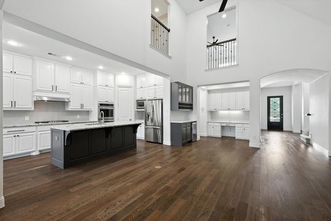 Kitchen featuring arched walkways, dark wood-style flooring, ceiling fan, white cabinets, and appliances with stainless steel finishes | Image 8