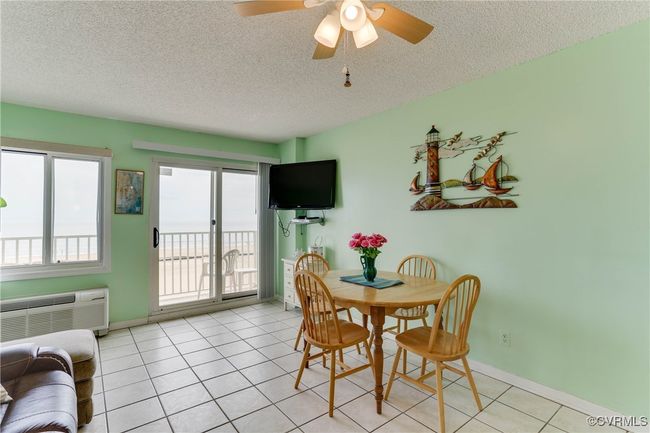 Dining area featuring light tile patterned floors, a textured ceiling, and an AC wall unit | Image 8