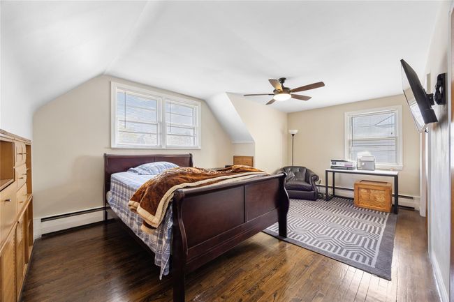 Bedroom featuring dark wood-style floors, multiple windows, vaulted ceiling, and a baseboard radiator | Image 10