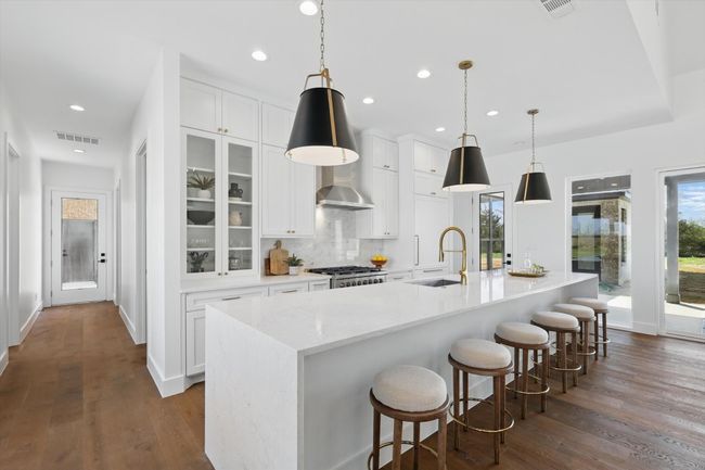 Kitchen featuring decorative backsplash, range, dark wood-style flooring, visible vents, and a sink | Image 7