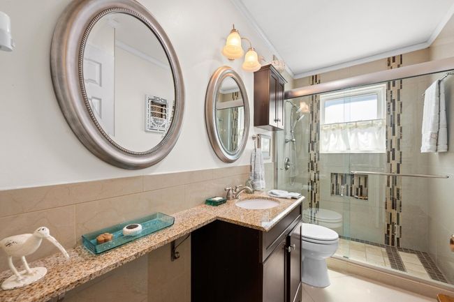 Bathroom featuring ornamental molding, toilet, tile walls, a shower stall, and tile patterned floors | Image 19