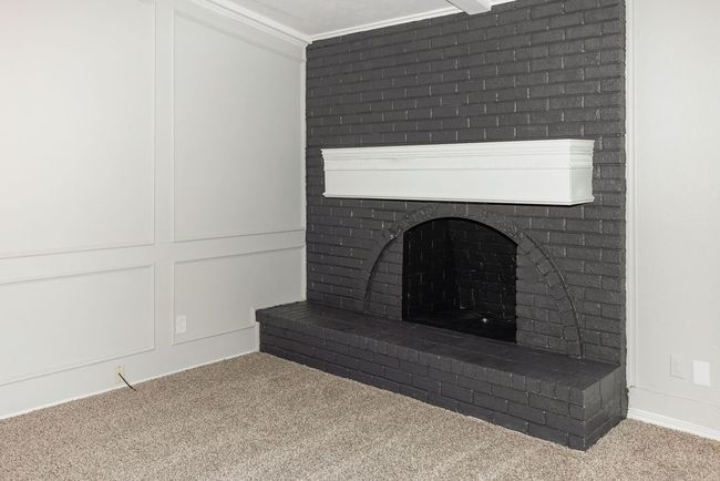 Details featuring a decorative wall, crown molding, carpet, and a brick fireplace | Image 15