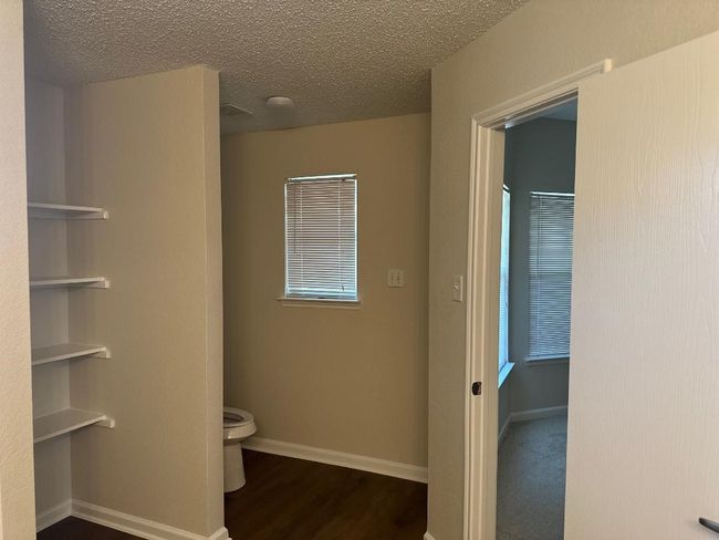 Bathroom featuring toilet, wood finished floors, baseboards, and a textured ceiling | Image 12