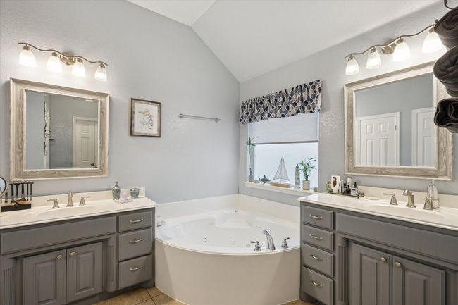 Full bath with lofted ceiling, his and hers vanities, a tub with jets, and tile patterned flooring | Image 23