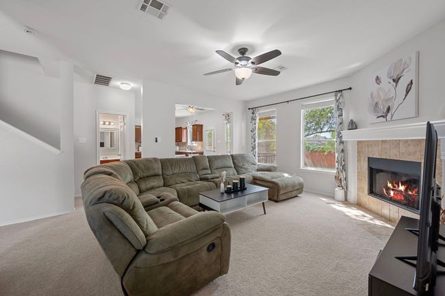 Carpeted living room with a ceiling fan, a fireplace, and baseboards | Image 9