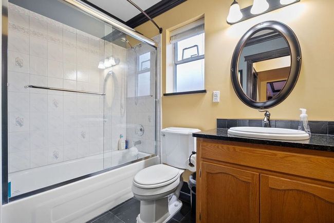 Full bath featuring toilet, shower / bath combination with glass door, tile patterned floors, and vanity | Image 28