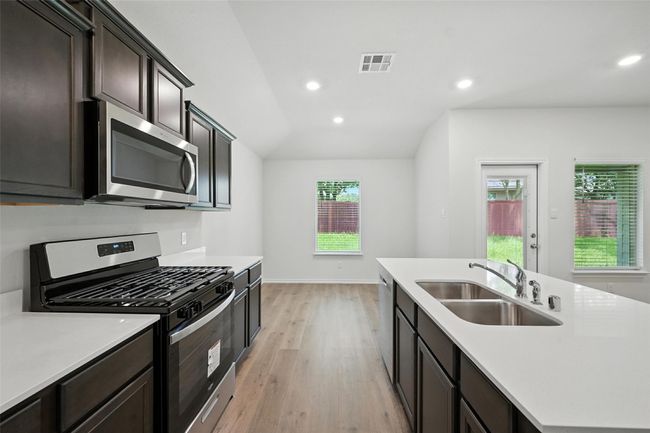 Kitchen with appliances with stainless steel finishes, light wood-type flooring, light countertops, an island with sink, and recessed lighting | Image 7