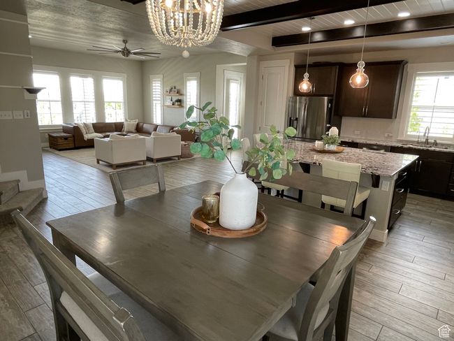 Dining space with ceiling fan with notable chandelier, wood-style tile, and beamed ceiling | Image 21