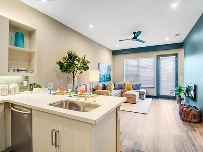Kitchen featuring light countertops, open floor plan, a sink, wood finished floors, and a peninsula | Image 4