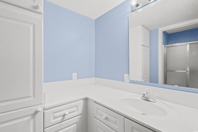 Bathroom featuring vanity, a textured ceiling, and an enclosed shower | Image 24