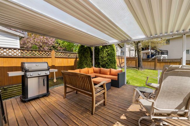 Wooden terrace with an outdoor living space, a fenced backyard, a yard, and a grill | Image 25