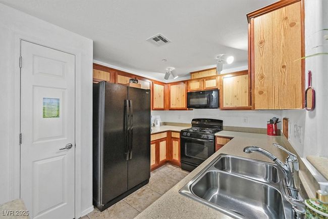 Kitchen featuring black appliances, light tile patterned floors, and light countertops | Image 9