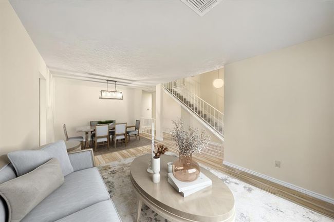 Open-concept living and dining space features a large seating area, neutral flooring, and direct access to the staircase. This photo has been virtually staged. | Image 8