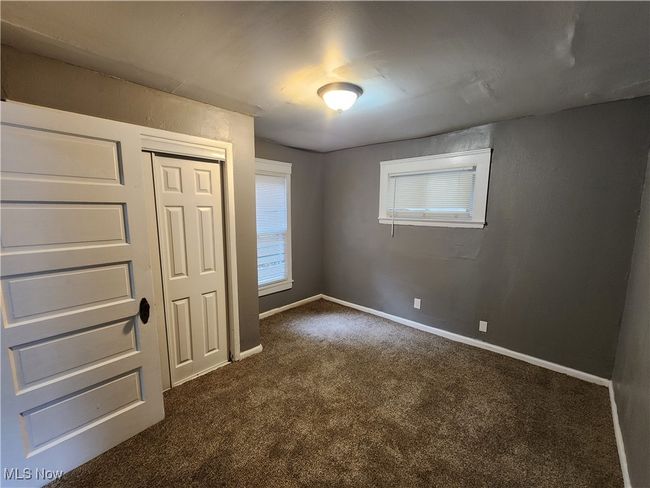 Unfurnished bedroom with a closet and dark carpet | Image 9