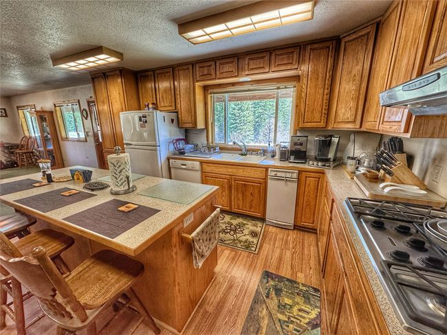 Kitchen with light wood finished floors, a sink, white appliances, and plenty of natural light | Image 16